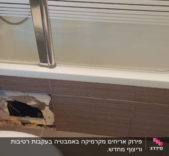 חור בקיר אמבטיה עם אריחים שבורים